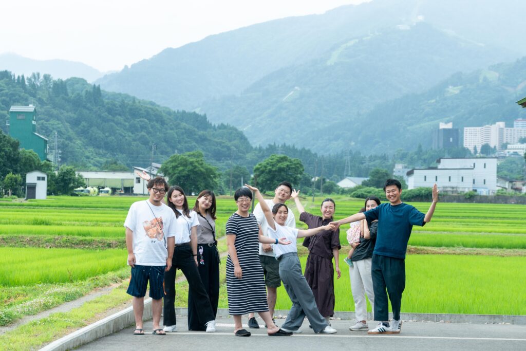 田園風景の前で笑顔を見せるきら星株式会社のスタッフたちの集合写真