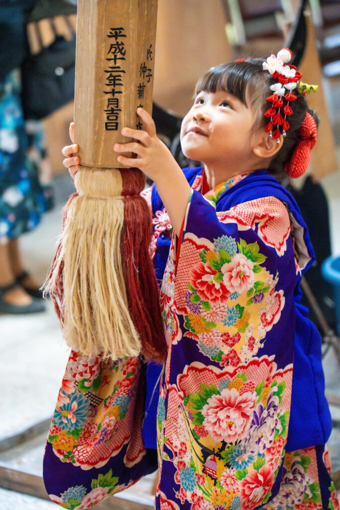 鈴緒を手にしてお参りする七五三の女の子（八海神社・南魚沼市）