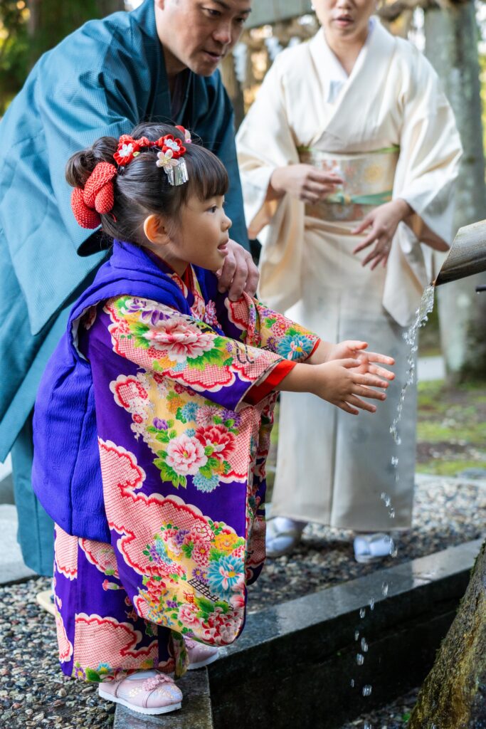 手水舎で清めをする七五三の女の子と両親（八海神社・南魚沼市）