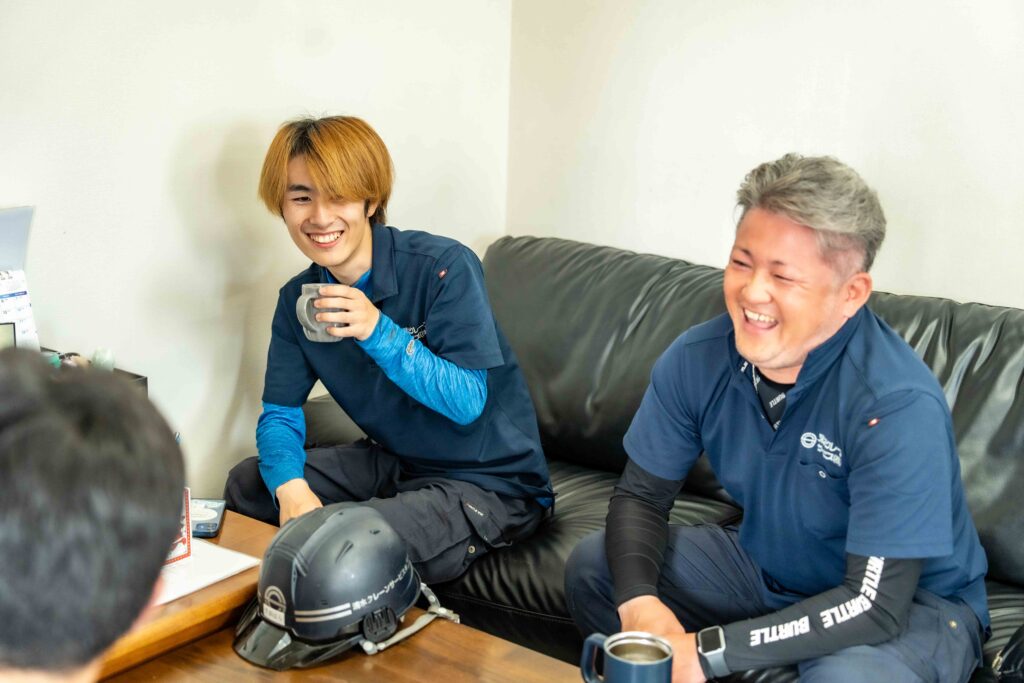 休憩室のソファでコーヒーを片手に談笑する若手社員と清水社長。アットホームで風通しの良い社風。