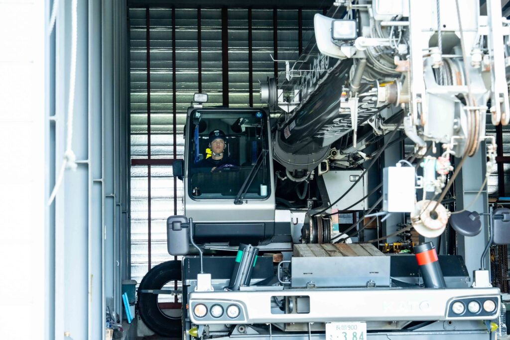 クレーン車の運転席に座り、真剣な表情で前方を確認する清水クレーンサービスの若手オペレーター。