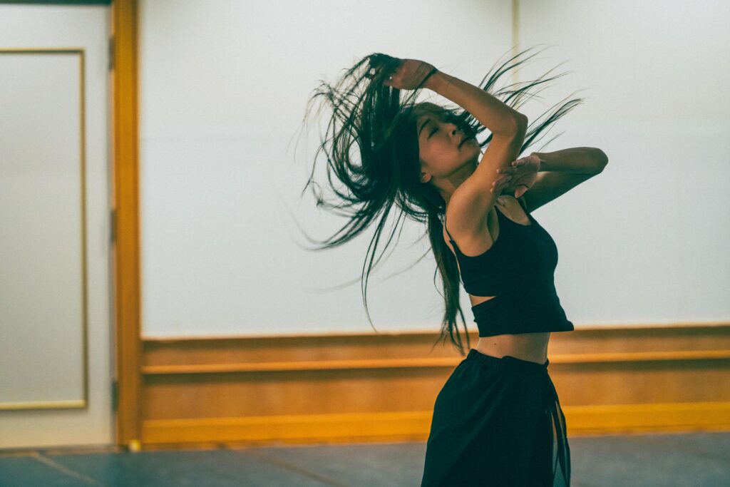 スポットライトを浴び、躍動的に髪をなびかせて踊るスタジオ・バレリータ主宰・真帆先生のアップ写真。情熱的な表情が印象的。